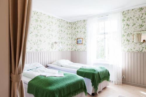 twee bedden in een kamer met groene dekens bij Amalia in Lemland