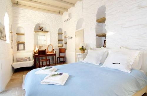 a bedroom with a blue bed in a white room at Aegean Bliss Villa - Hydroussa in Andros
