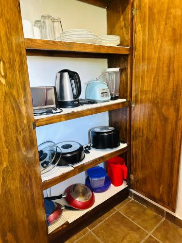 a kitchen shelf with dishes and pots and pans at CABO BOHEMIA Tropical Garden Studios in Cabo San Lucas