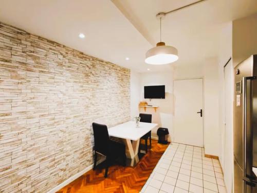 Una habitación con una mesa blanca y una pared de ladrillos. en Mini-studio avec kitchenette OU chambre confort avec frigo et TV - Parking en option sur résa !, en Chaville