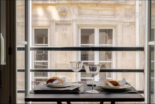 - une table avec deux assiettes de nourriture et des verres à vin dans l'établissement St Germain des Prés Appart, à Paris