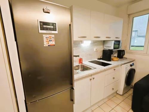 Una cocina con frigorífico de acero inoxidable y fregadero. en Mini-studio avec kitchenette OU chambre confort avec frigo et TV - Parking en option sur résa !, en Chaville
