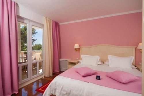 a bedroom with pink walls and a bed with pink pillows at Apartments and Room Luxury dream in Brela