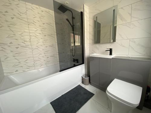 a bathroom with a tub and a toilet and a sink at Central Cheerful Comfortable 3 Bedroom Home in Pallion