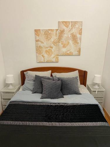 a bedroom with a bed with two tables and two pictures on the wall at Casa de Vasco-Estadia Familiar e Tranquila in Amora