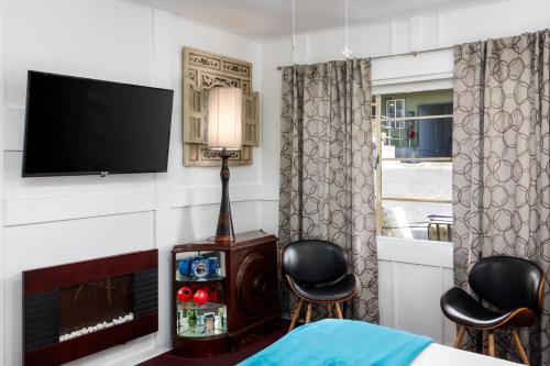 a bedroom with a tv and two chairs and a fireplace at The Motor Lodge in Prescott