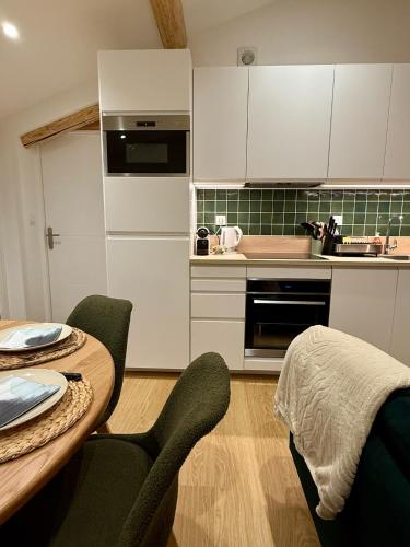 a kitchen with white cabinets and a table and chairs at Appt Rénové et Moderne - 3 chambres - Châtel - Multi Pass - MÉNAGE INCLUS in Châtel