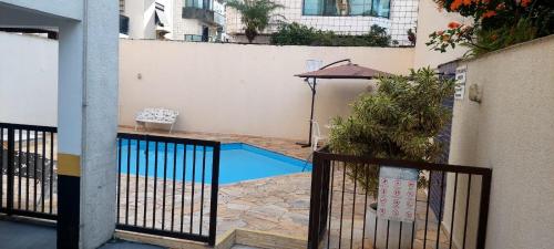 a small swimming pool with an umbrella in a courtyard at Apartamento em Enseada Guarujá in Guarujá
