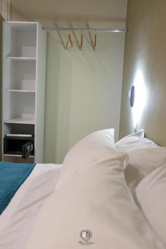 a bedroom with a bed with white sheets and a shelf at Palazzo Giudecca in Reggio Calabria