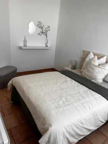 une chambre avec un grand lit avec des draps et des oreillers blancs dans l'établissement Appartement entre aéroport et promenade des anglais, à Nice