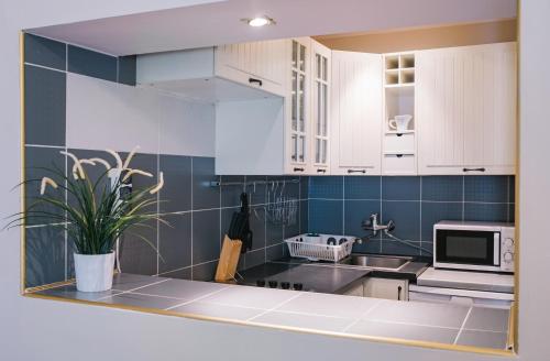 Una cocina con gabinetes blancos y una planta en maceta. en Rembrandt Aparthotel, en Cracovia