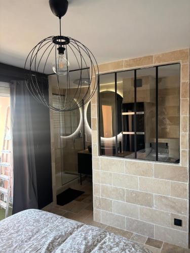 Una lámpara de araña en un dormitorio con una pared de ladrillos. en Appartement d Alex, en Joué-lès-Tours