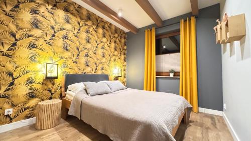 a bedroom with a bed and a yellow wall at Przystanek Jaworki - Apartament w Jaworkach in Szczawnica