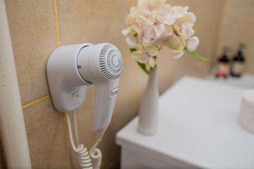 a blow dryer in a bathroom with a vase of flowers at Urban Escape Arad in Arad