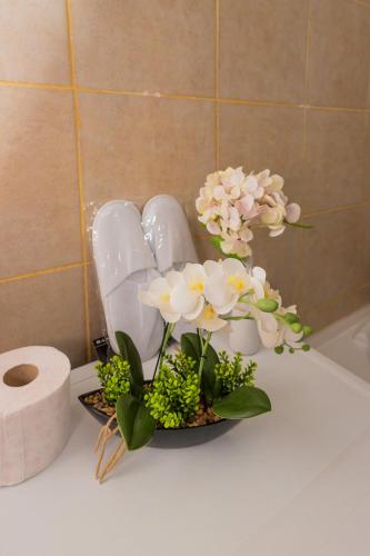 a bathroom counter with flowers and a roll of toilet paper at Urban Escape Arad in Arad