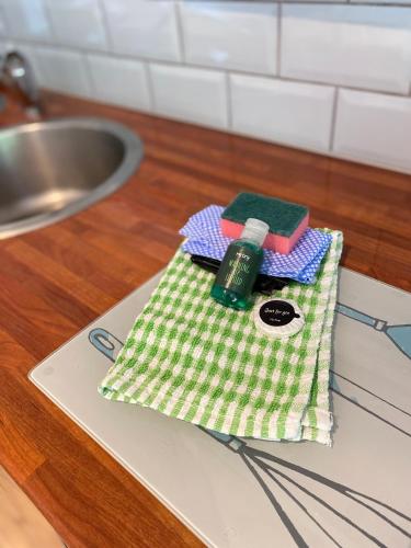 a green and white towel with a bottle on a counter at Little Wight House - Yarmouth in Freshwater