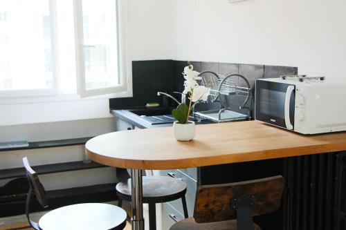une cuisine avec une table, un four micro-ondes et une table avec des chaises dans l'établissement La Suite Savonnerie, à Rouen