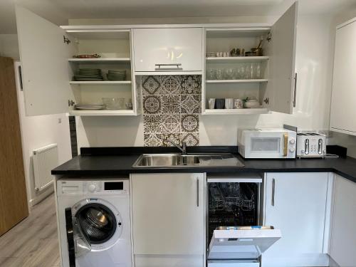 a kitchen with a sink and a washing machine at Brand new Modern 1 bedroom bungalow with front & back gardens Central Headington in Oxford