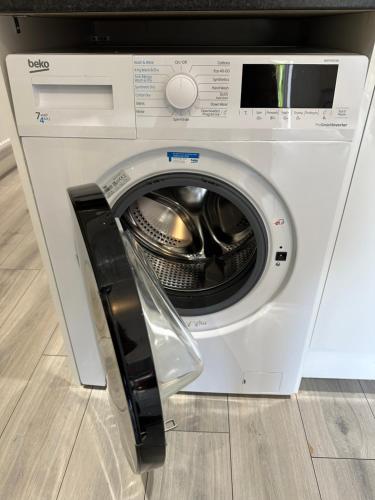 a washing machine with its door open in a room at Brand new Modern 1 bedroom bungalow with front & back gardens Central Headington in Oxford
