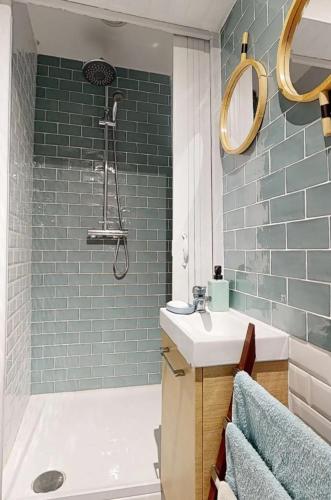 une salle de bain avec un lavabo et une douche avec du carrelage bleu dans l'établissement Studio cosy à Paris 12m² avec terrasse privée, à Paris
