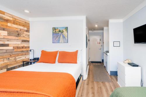 a bedroom with two beds with orange pillows and a tv at Mountainside Inn 111 by Alpine Lodging Telluride in Telluride