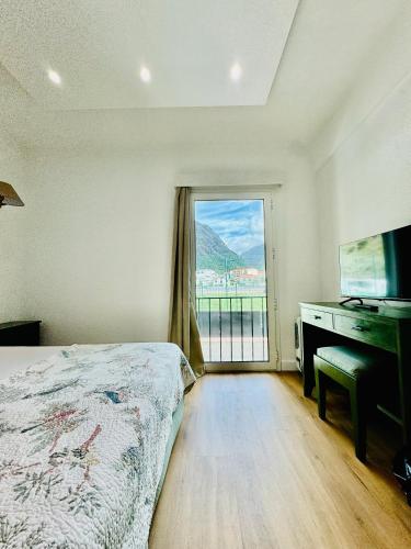 a bedroom with a bed and a desk and a window at VALE MAR Guest in Ribeira Brava