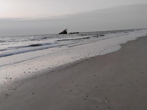 a sandy beach with a lighthouse in the ocean at Hôtel Nanaay in Palmarin