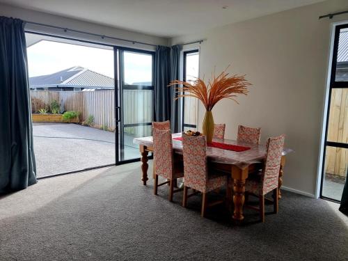 a dining room with a table and chairs and a glass door at Modern house close to lake,golf club and beach in Woodend