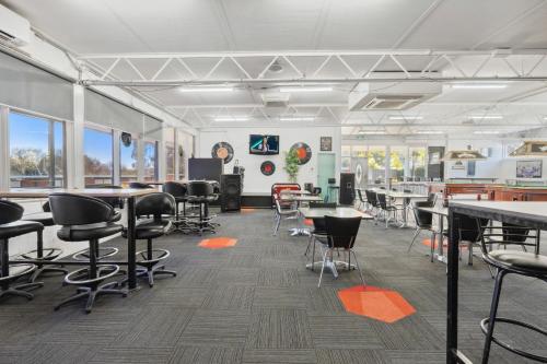 a classroom with tables and chairs in a room with windows at Southside Village in Canberra