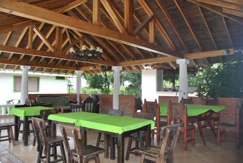 a patio with green tables and chairs under a wooden roof at Hotel La Coqueta in Montenegro