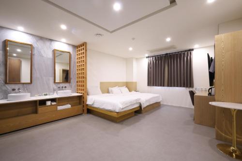 a bedroom with a bed and a sink and a mirror at TRT Hotel in Busan