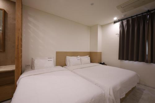 two beds in a room with white sheets at TRT Hotel in Busan