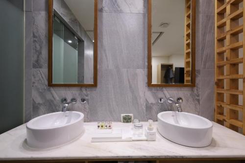 two sinks in a bathroom with two mirrors at TRT Hotel in Busan