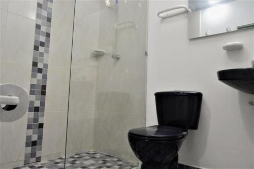 a bathroom with a black toilet and a glass shower at Apto 301 - Remodelado, iluminado y buena vista - Casa Orquídeas in Fusagasuga