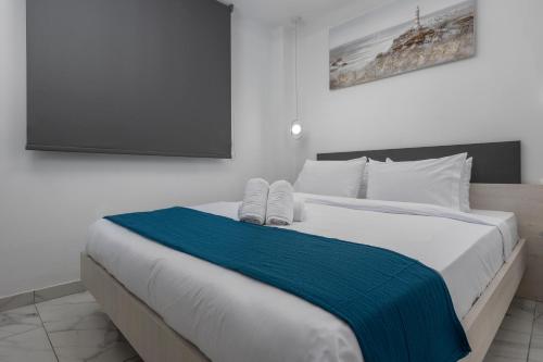 a white bed with a blue blanket and a flat screen tv at PREMIUM JACUZZI SUITE at the City center, by Aqua Platinum in Thessaloniki