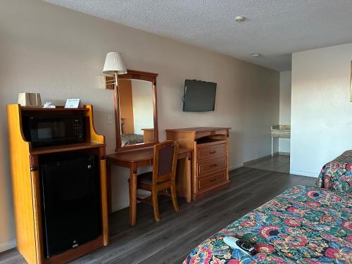 ein Hotelzimmer mit einem Schlafzimmer mit einem Bett und einem Schreibtisch in der Unterkunft Regal Inn Las Vegas New Mexico in Las Vegas