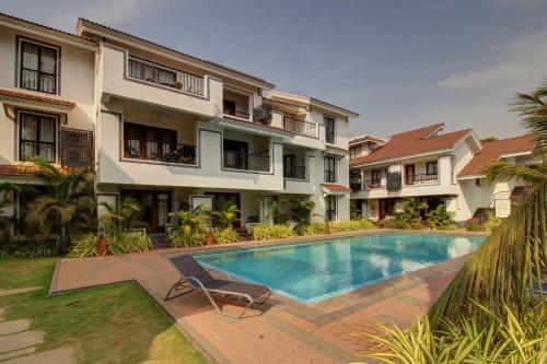 a villa with a swimming pool in front of a building at Dream key suits in Siolim