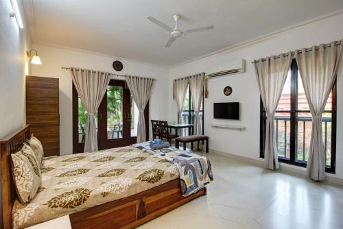 a bedroom with a bed and a tv and windows at Dream key suits in Siolim