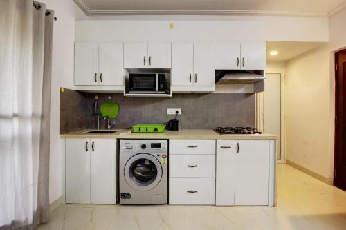 a kitchen with white cabinets and a washing machine at Dream key suits in Siolim