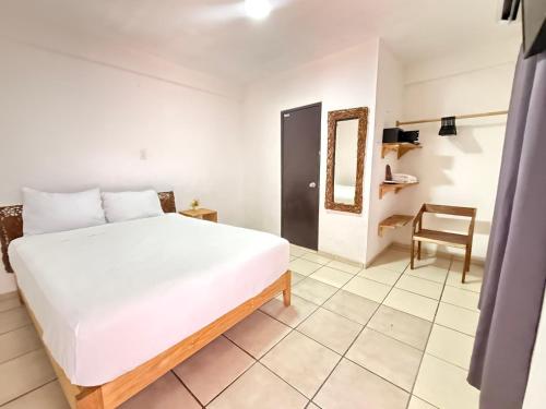 een slaapkamer met een wit bed en een stoel bij Hotel Casa Caracol in Isla Mujeres