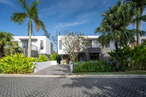 a house with palm trees in front of a street at Montgomerie Links Hotel & Villas in Hoi An