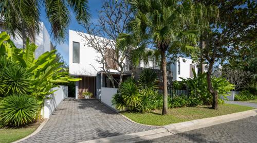 a white house with palm trees and a sidewalk at Montgomerie Links Hotel & Villas in Hoi An