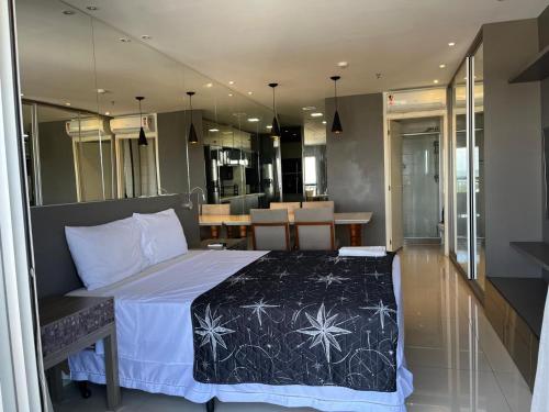 a bedroom with a large bed and a dining area at M&V Flats - Prédio Vision - 1,5 km Mané Garrincha - 500m Esplanada dos Ministérios - Vaga de garagem - Ar condicionado - Cama queen size - Piscina - Academia in Brasilia