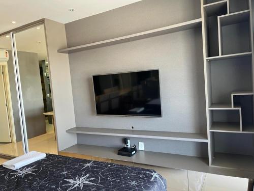 a bedroom with a flat screen tv on a wall at M&V Flats - Prédio Vision - 1,5 km Mané Garrincha - 500m Esplanada dos Ministérios - Vaga de garagem - Ar condicionado - Cama queen size - Piscina - Academia in Brasilia