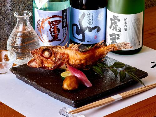 a piece of meat on a black plate with bottles of wine at Hotel Grand Tiara Minaminagoya in Anjo