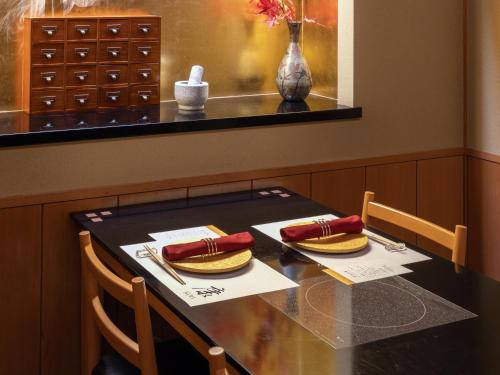 a table with two chairs and a table with two hot dogs at Hotel Grand Tiara Minaminagoya in Anjo