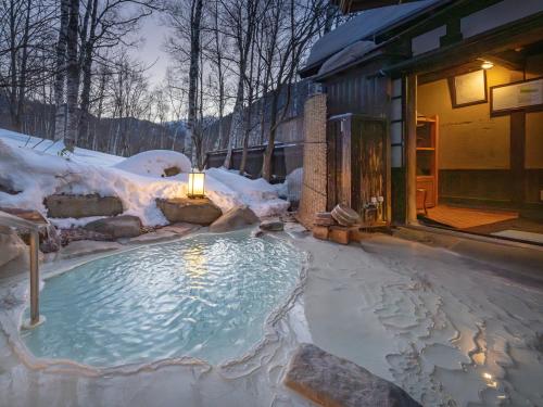 a hot tub covered in snow next to a building at Konashi No Yu Sasaya in Matsumoto