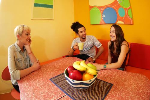 three people sitting around a table with a bowl of fruit at Banana Bungalow Hollywood Hotel & Hostel in Los Angeles