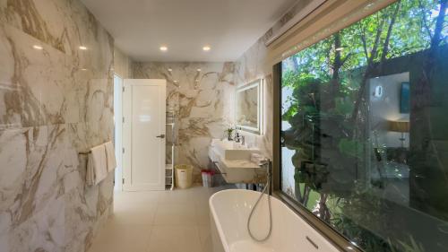 une salle de bains avec baignoire et lavabo dans l'établissement Beachfront Luxury villa near Banyan Tree, à Layan Beach