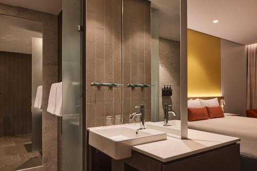 a bathroom with a sink and a bed at Rydges Sydney Airport Hotel in Sydney